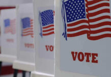 Illegal Voting Bombshell – State Balks Voting booths with American flags and VOTE signs.