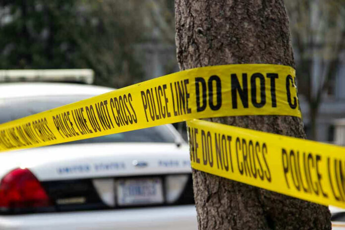 789649249 Police tape surrounding a tree and police car.