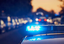 Police investigation at a crime scene with a covered body and evidence markers