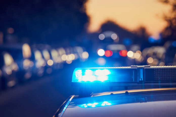 Police investigation at a crime scene with a covered body and evidence markers