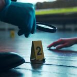 Gypsy Rose Shocker: Partner Found Dead A detective examining evidence at a crime scene with markers on the floor