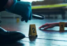 A detective examining evidence at a crime scene with markers on the floor
