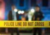Deadly Police Power Trip Police tape at a night scene with blurred officers in the background