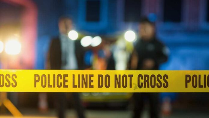 "do-not-cross",Tapes,Restricting,Access,To,Crime,Scene,In,A,Back Police tape at a night scene with blurred officers in the background
