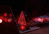 Mega-Church Hack Exposes Massive Flock Warning symbol over laptop with user.