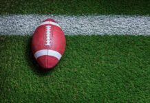 Football on a green field near a white yard line