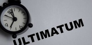 A black alarm clock next to the word 'ULTIMATUM' on a gray background