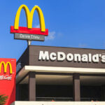 Million-Dollar Comeback: McDonald’s Plays Dirty-Smart McDonald's restaurant exterior with drive-thru signs against blue sky