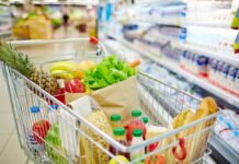 Grocery Giant Clash: Who Blinks First? A shopping cart filled with fresh fruits, vegetables, and groceries