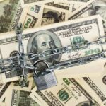 Paychecks Exposed – Treasury Slams Brakes A stack of hundred dollar bills secured with a chain and padlock